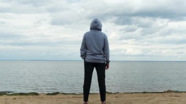 Finlandiya Körfezi, Saint Petersburg, Rusya 'daki bir erkeğin arka görüntüsü. Kavram. Spor elbiseli bir adamın kumsalda dikilip uzak diyarlara bakışıyla..