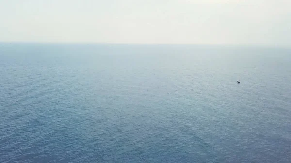 Blick von oben auf Segelboote und einen Mann, der im offenen Meer schwimmt. Video. Erstaunliche Luftaufnahme zweier weißer Yachten im tiefblauen Meer vor dem endlosen Horizont. — Stockfoto