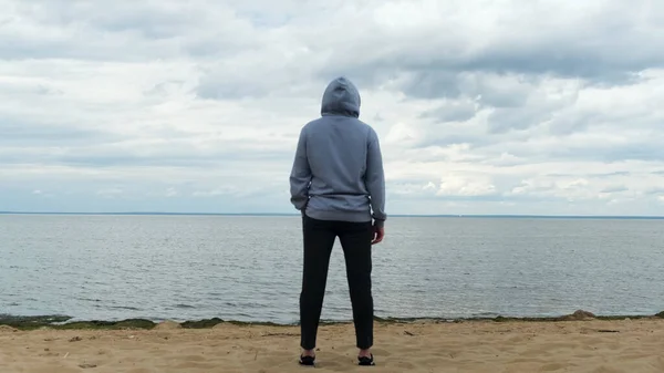 Πίσω όψη αρσενικού στον Κόλπο της Φινλανδίας, Αγία Πετρούπολη, Ρωσία. Έννοια. Οπίσθια όψη ενός άνδρα με αθλητικά ρούχα που στέκεται στην παραλία και κοιτάζει μακριά στο βάθος. — Φωτογραφία Αρχείου