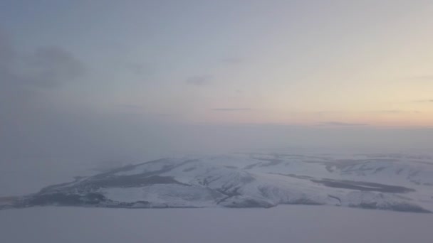 Karlı dağlardaki sisli sabahın hava görüntüsü. Stok görüntüleri. Sonsuz kar çölü ve bulutlu arka planda tepeler, kış doğal arka plan. — Stok video