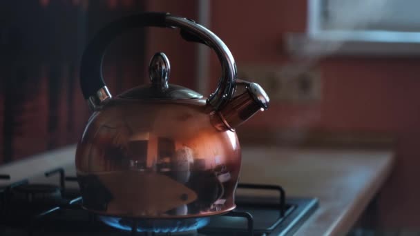 Zamykam herbatę na parze. Koncepcja. Grzejnik świecący pod stalowym czajnikiem polerowanym z wrzącą wodą i odbiciem kuchni na jego powierzchni. — Wideo stockowe