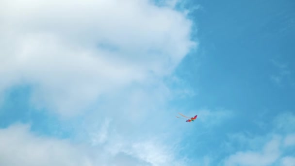 Bulutların arasında uçan uçurtma. Kavram. Beyaz bulutlu mavi gökyüzü ve yükselen gökkuşağı renkli uçurtma, özgürlük ve çocukluk kavramı.. — Stok video