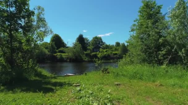 Landskap med gammalt trähus på sjön med båt. Skjuten. Ljus sommardag på byn med gröna träd och äng, boende på ekologisk plats. — Stockvideo