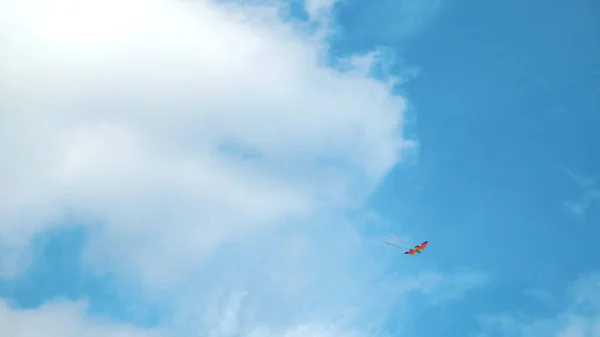 Cerf-volant volant dans le ciel parmi les nuages. Concept. Vue du fond du ciel bleu d'été avec nuages blancs et cerf-volant coloré arc-en-ciel, concept de liberté et d'enfance. — Photo
