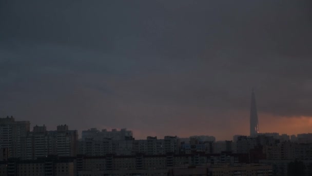 Lakhta Center em São Petersburgo ao pôr do sol, Rusia. Conceito. Edifício alto da elevação cercado por casas residenciais, centro de negócios no fundo pesado do céu do por do sol, efeito do lapso de tempo . — Vídeo de Stock