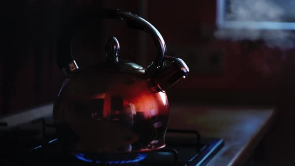 Bollitore lucido bollente su una stufa a gas in cucina la sera. Concetto. Primo piano di bollitore bollente con il vapore proveniente da teiera in metallo su forno a gas. — Video Stock