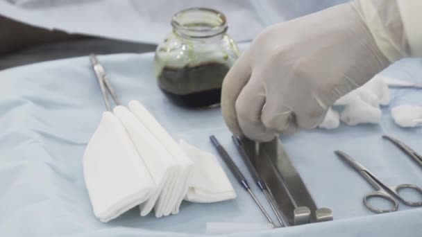 Närbild av sterila kirurgiska verktyg för operationen. Börja. Hand av en läkare i skyddande ren handske som tar ett speciellt instrument för operation. — Stockvideo
