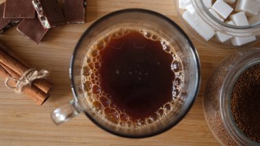 Masanın üzerindeki fincanda sade kahve. Çikolata ve tarçınlı kompozisyon. Kavram. Kamera ekranındaki kahve buharının üst görüntüsünü kapat..
