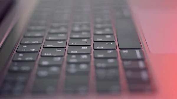 Prospettiva di un computer moderno o una tastiera nera portatile su sfondo rosa, vista da vicino. Azione. Nuova tastiera con pulsanti neri e simboli bianchi su di essi, concetto di tecnologie moderne. — Foto Stock