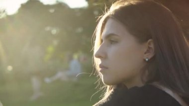 Güneş ışığının arka planında güzel bir kadının profili. Medya. Sıcak güneş ışınları parktaki güzel kadınların saçlarına düşer. Romantik kadın güneşin arka planında saçları düzleştiriyor.