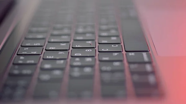 Primo piano di pulsanti sulla tastiera del computer, sfondo macro. Azione. Pulsanti di computer portatile moderni neri sotto la luce di lampada rossa, concetto di tecnologie e dispositivi. — Foto Stock