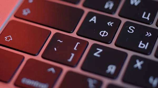 Cierre de botones en el teclado del ordenador, fondo de macro. Acción. Botones modernos negros del ordenador portátil bajo la luz roja de la lámpara, concepto de tecnologías y dispositivos. — Foto de Stock