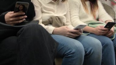 Metroda telefonlarda oturan bir kadının yakın çekimi. Medya. Metroda insanlar akıllı telefon kullanır. Metroda akıllı telefon bağımlılığı