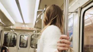 Kulaklıklı genç bir kadın metrodan çıkıyor. Medya. Kulaklık takan öğrenci metroya biniyor ve istasyonunda iniyor. Metro trenleri