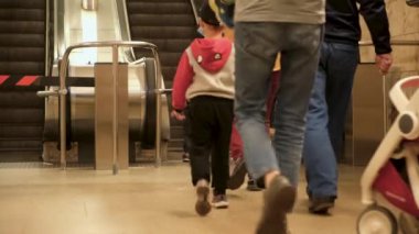 Çocukları olan insanlar metroda yürüyen merdivene tırmanıyorlar. Medya. Çocuklu aileler asansöre binip metroya biniyor. Metroda küçük çocukları olan insanlar.