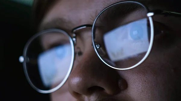 Κοντινό πλάνο του ανθρώπου με τα γυαλιά κοιτάζοντας τον υπολογιστή το βράδυ. Έννοια. Το να δουλεύεις στον υπολογιστή στο σκοτάδι κάνει κακό στην όρασή σου. Ο άνθρωπος με τα γυαλιά κοιτάζει προσεκτικά τον υπολογιστή στο σκοτάδι. — Φωτογραφία Αρχείου