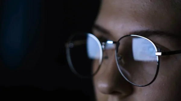 Zbliżenie kobiety w okularach patrzącej na komputer w ciemności. Koncepcja. Kobieta w okularach napinająca oczy czytając artykuły na komputerze w ciemności — Zdjęcie stockowe