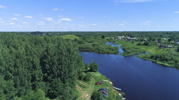 Draufsicht auf grünen Wald mit Flüssen und Dorf am Horizont mit blauem Himmel. Schuss. Schöne Sommerlandschaft mit grünen Wäldern und blauen Flüssen — Stockfoto