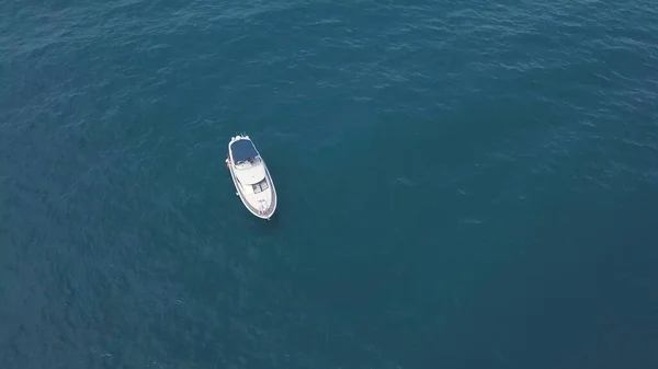Top view of alone yacht floating in turquoise water. Clip. Yacht floating alone in open blue ocean. Sea trip on yacht in open ocean