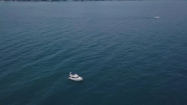 Yate sobre fondo de costa con ciudad en clima nublado. Clip. Vista superior del paisaje marino con la costa de fondo yate solo y el cielo oscuro — Foto de Stock