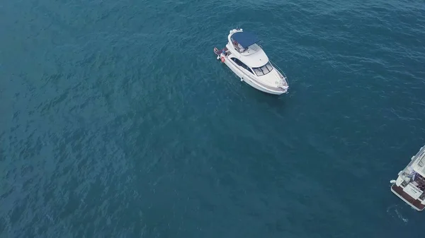 Vista superior del yate con gente flotando en agua turquesa. Clip. Los turistas se relajan y se divierten en yate solo en mar abierto. La gente nada cerca de yate en mar abierto —  Fotos de Stock