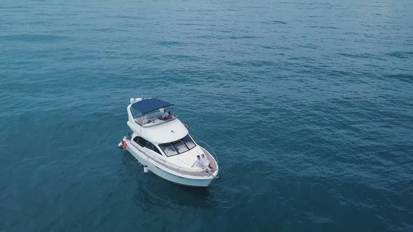 Vue de dessus du yacht avec des gens flottant dans l'eau turquoise. Clip. Les touristes se détendent et s'amusent sur un yacht seul en haute mer. Les gens nagent près du yacht en haute mer — Photo