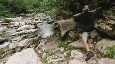 Taşların üzerinde nehri geçen iki yolcu. Şarjör. Genç gezginler taşların üzerinde orman nehrini geçiyorlar. Kayaların üzerinden geçen ilk kişinin vurulması. Ormandaki adamların yaz macerası