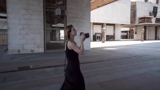 Mujer toma fotos con cámara de arquitectura de edificios modernos. Acción. Mujer con cámara profesional toma fotos de edificios de arquitectura moderna — Vídeos de Stock