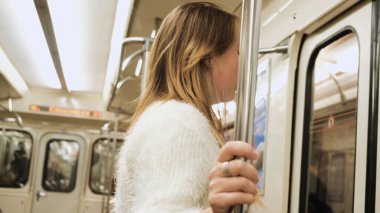 Kulaklıklı genç bir kadın metrodan çıkıyor. Medya. Kulaklık takan öğrenci metroya biniyor ve istasyonunda iniyor. Metro trenleri