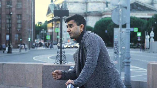 Joven espera reunión en la calle en el centro de la ciudad. Medios. El hombre atractivo está esperando a su novia en el cruce en el fondo de la calle concurrida por la noche — Foto de Stock