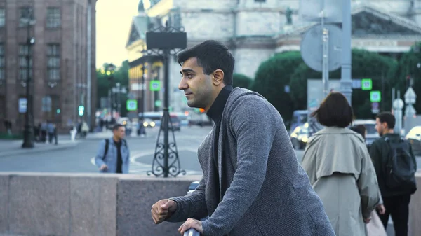 Joven espera reunión en la calle en el centro de la ciudad. Medios. El hombre atractivo está esperando a su novia en el cruce en el fondo de la calle concurrida por la noche — Foto de Stock