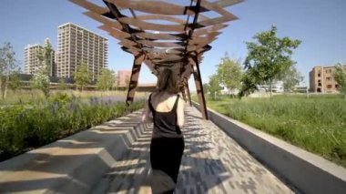 Güzel bir kadın modern şehir parkının mimarisinin fotoğraflarını çekiyor. Başla. Güzel bir kadın yeşil şehir parkında profesyonel kamera ve pavyonlarla fotoğraf çekiyor.