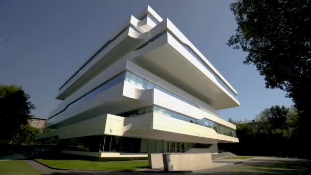 Frumoasă fațadă albă a clădirii de birouri futuriste. Acţiune. Fațada centrului de afaceri în stil avangardist pe cerul albastru de fundal. Neomodernism și deconstructivism în arhitectura clădirilor de birouri — Videoclip de stoc