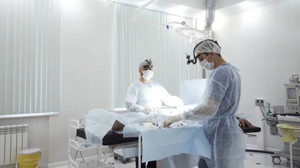 Two male surgeons at the work with time lapse effect. Action. Sedated patient lying on the table during surgical procedure inside the hospital room. — Stock Photo, Image