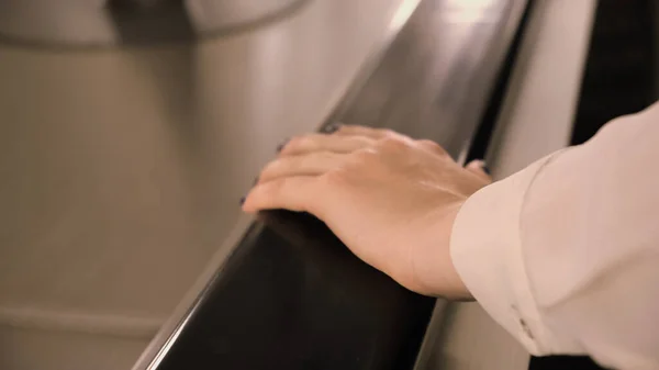 ผู้หญิงส่งบันไดเลื่อน สื่อ ใกล้ชิดของผู้หญิงมือบนบันไดเลื่อนย้ายขึ้น มือผู้หญิงโดดเดี่ยวบนรางบันไดเลื่อนในรถไฟใต้ดิน — ภาพถ่ายสต็อก
