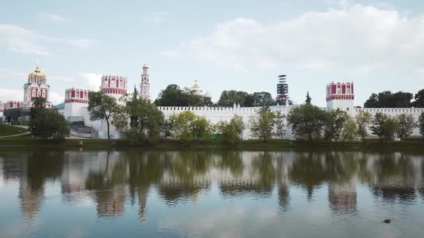 Conjunto do mosteiro com lagoa. Acção. Bela paisagem com mosteiro cercado por muro branco por lagoa. Paisagens russas de mosteiros — Vídeo de Stock