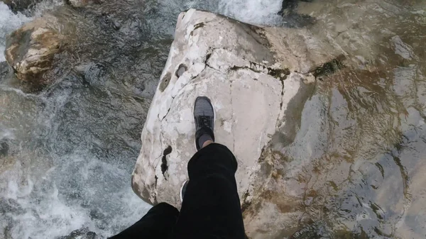 Paisaje natural de río montañoso con un hombre saltando de piedra en piedra. Clip. Disparos en primera persona de piernas masculinas cruzando el río de flujo rápido con grandes piedras en el bosque salvaje. — Foto de Stock