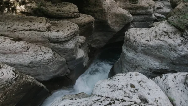 Waterstroom van bergachtige rivier stroomt tussen rotsen in de smalle kloof. Een knip. Waterstroom met koud zoet water en veel witte rotsblokken. — Stockfoto