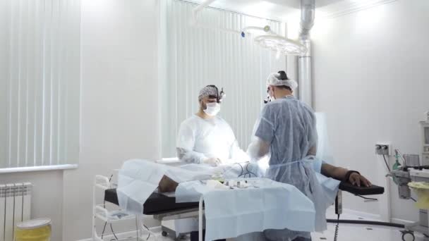 Twee mannelijke chirurgen op het werk met time lapse effect. Actie. Verdoofde patiënt liggend op de tafel tijdens chirurgische ingreep in de ziekenhuiskamer. — Stockvideo