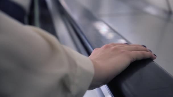 Κοντινό πλάνο της γυναίκας χέρι κρατώντας το τιμόνι της κυλιόμενης σκάλας. Μέσα ενημέρωσης. Νεαρή καυκάσια γυναίκα χέρι σε μαύρο χειρολισθήρα στο σταθμό του μετρό. — Αρχείο Βίντεο
