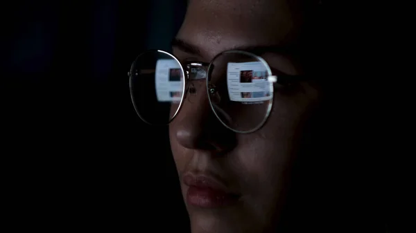 Κοντινό πλάνο της κουρασμένης γυναίκας που δουλεύει τη νύχτα στο λάπτοπ. Έννοια. Κορίτσι με γυαλιά ματιών με αντανακλάσεις υπερεργασίας απασχολημένος, χρησιμοποιώντας τον υπολογιστή στο σκοτεινό γραφείο, ψάχνει και περιήγηση σε σημαντικά δεδομένα. — Φωτογραφία Αρχείου