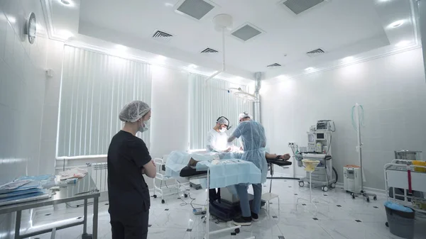 Team of surgeons and nurses during operation. Action. Nurse watches operation and waits for team to help surgeons. Outside view of operation under anesthesia — Stock Photo, Image