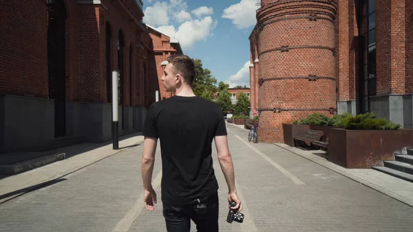 Jovem tira fotos de belos edifícios. Acção. Guy tira fotos na câmera profissional enquanto caminha pela cidade. Homem atraente tira fotos profissionais da arquitetura urbana — Fotografia de Stock