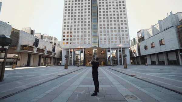 Człowiek fotografuje piękny nowoczesny budynek w mieście. Akcja. Profesjonalny młody fotograf robi zdjęcia popularnych nowoczesnych budynków. Zwiedzanie Rosji. Budowa RAS — Zdjęcie stockowe