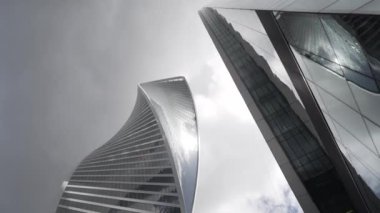 Arka plandaki bükülmüş cam gökdelenin alt görüntüsü. Başla. Modern fütüristik mimarlık sektörünün yükselişi gökyüzünü ve güneşi yansıtıyor. Moskova İş Merkezi - Moskova Şehri