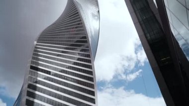 Arka plandaki bükülmüş cam gökdelenin alt görüntüsü. Başla. Modern fütüristik mimarlık sektörünün yükselişi gökyüzünü ve güneşi yansıtıyor. Moskova İş Merkezi - Moskova Şehri