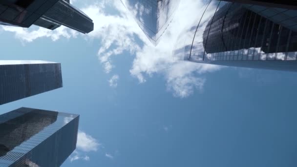 Vista in basso di cime di grattacieli di vetro su sfondo cielo blu. Azione. Architettura moderna di centri commerciali che riflettono il cielo blu. Vista vertiginosa dei moderni grattacieli di vetro — Video Stock