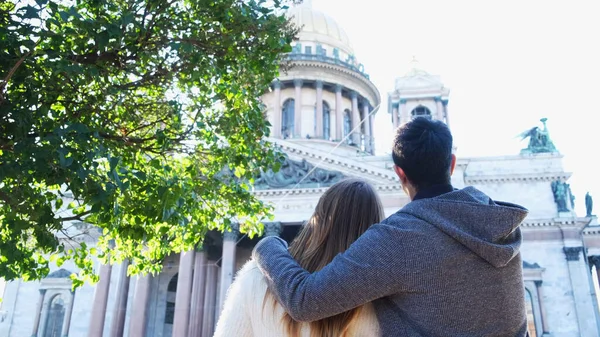 Les amoureux embrassent dans le contexte de la cathédrale Saint Isaacs, Saint-Pétersbourg. Concept. Vue arrière de touristes homme et femme regardant le bâtiment historique en été. — Photo