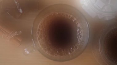Masanın üzerindeki fincanda sade kahve. Çikolata ve tarçınlı kompozisyon. Kavram. Kamera ekranındaki kahve buharının üst görüntüsünü kapat..