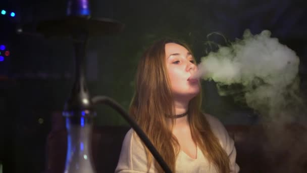 Mujer soltera fuma hookah maravillosamente. Medios. Mujer joven deja salir nubes de humo mientras enciende narguile. Arte de fumar narguile — Vídeos de Stock